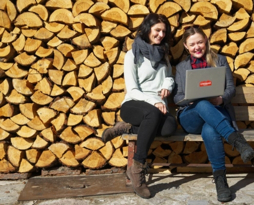 zwei-Frauen-mit-Laptop-Holzstoss